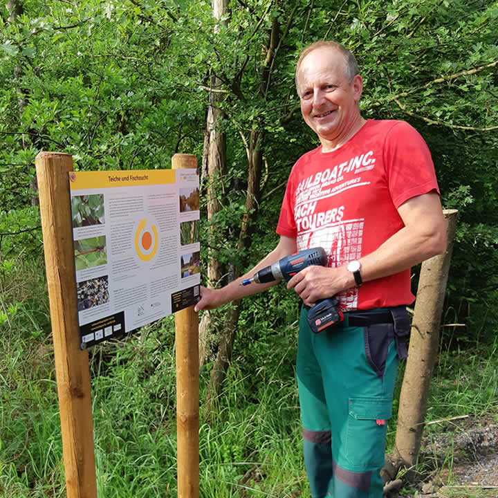 Rainer Möckel, Mitarbeiter des Landratsamtes, bei der Befestigung eines der Arnika-Infoschilder
